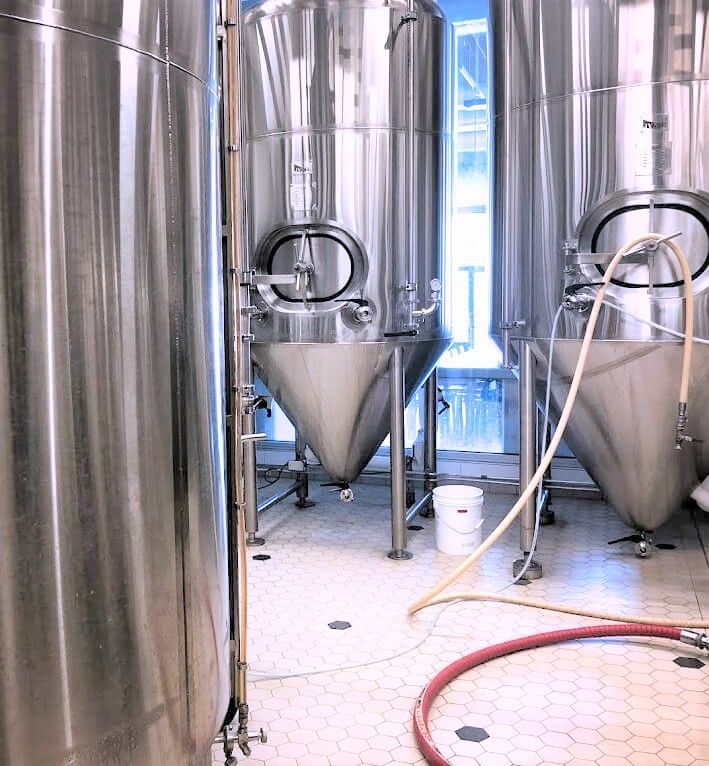 A room filled with stainless steel tanks and a hose.