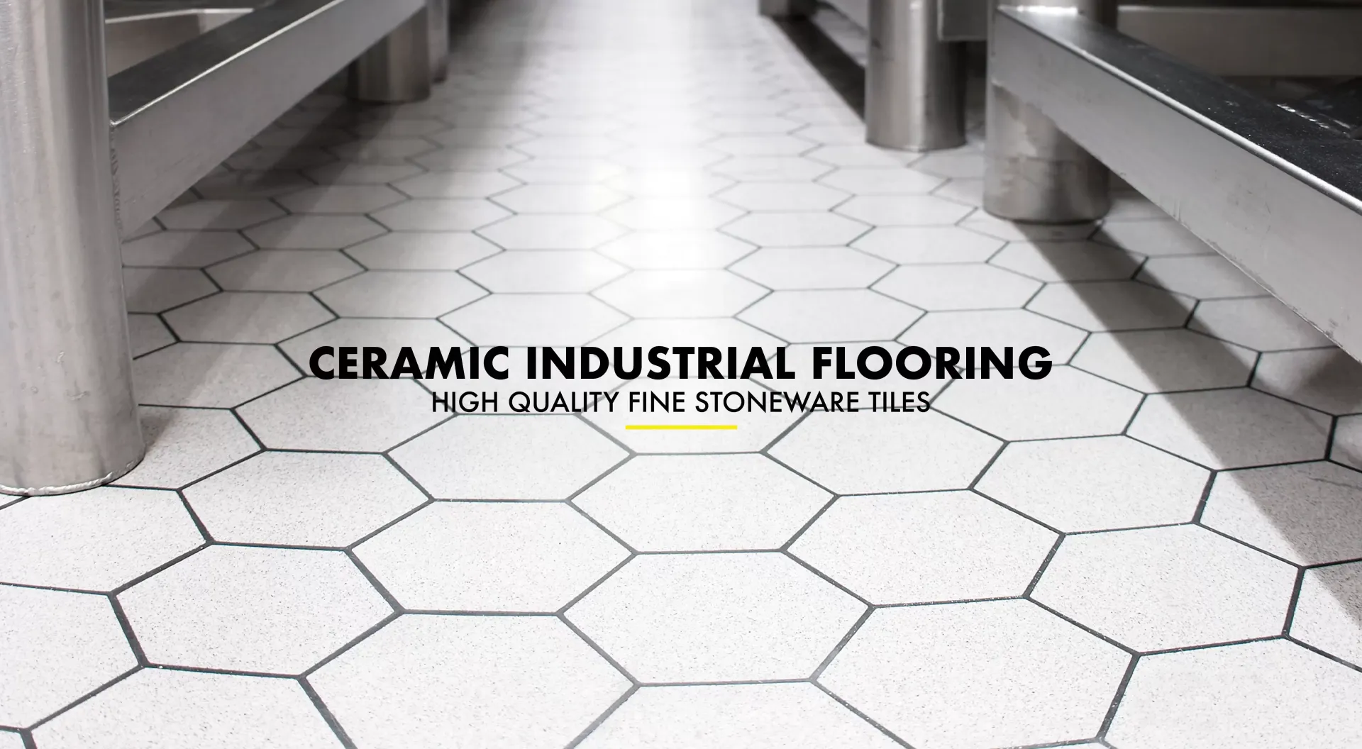 White hexagonal ceramic floor tiles in an industrial kitchen setting with stainless steel equipment.