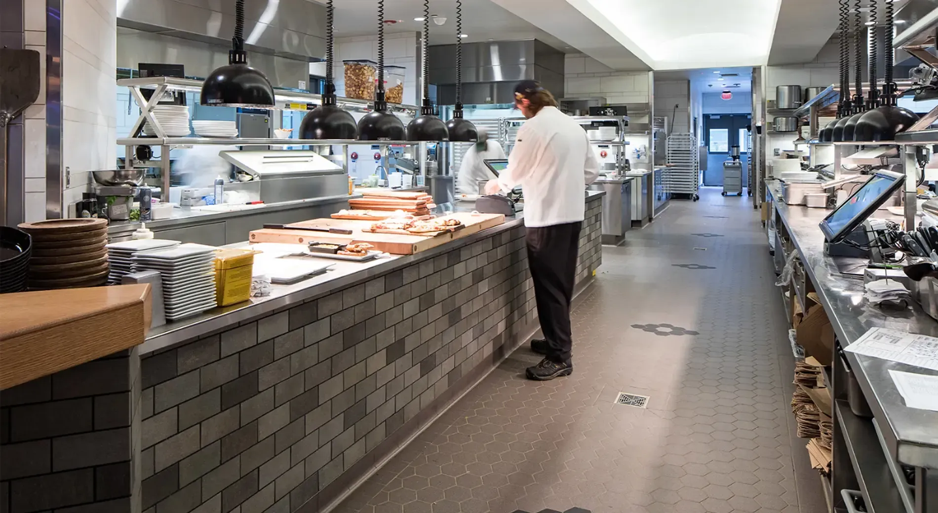 A chef is standing at a counter in a restaurant kitchen.