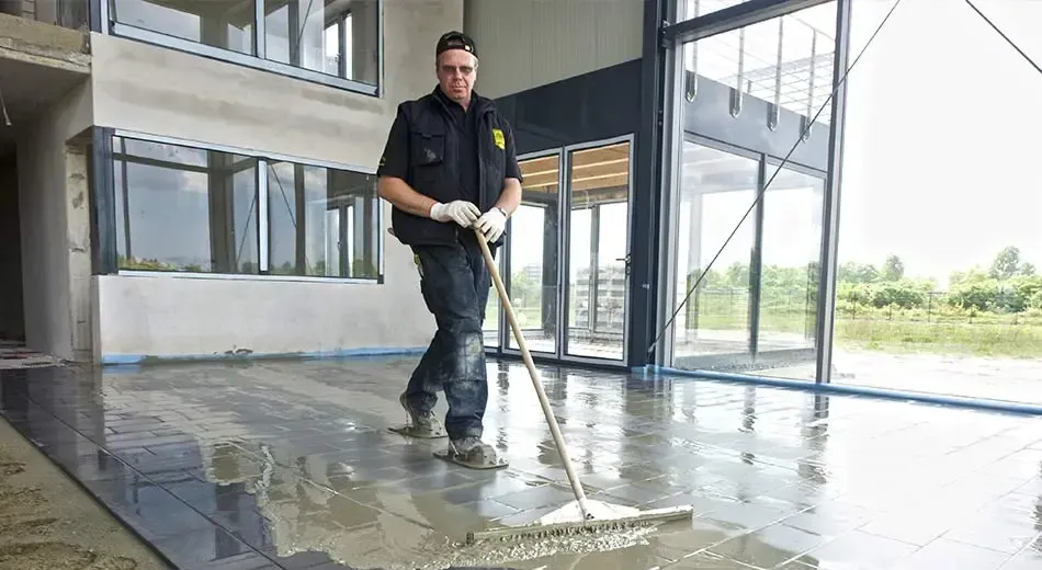 A man is cleaning the floor of a building with a broom.