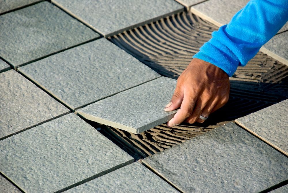 A person is laying tiles on a tiled floor.