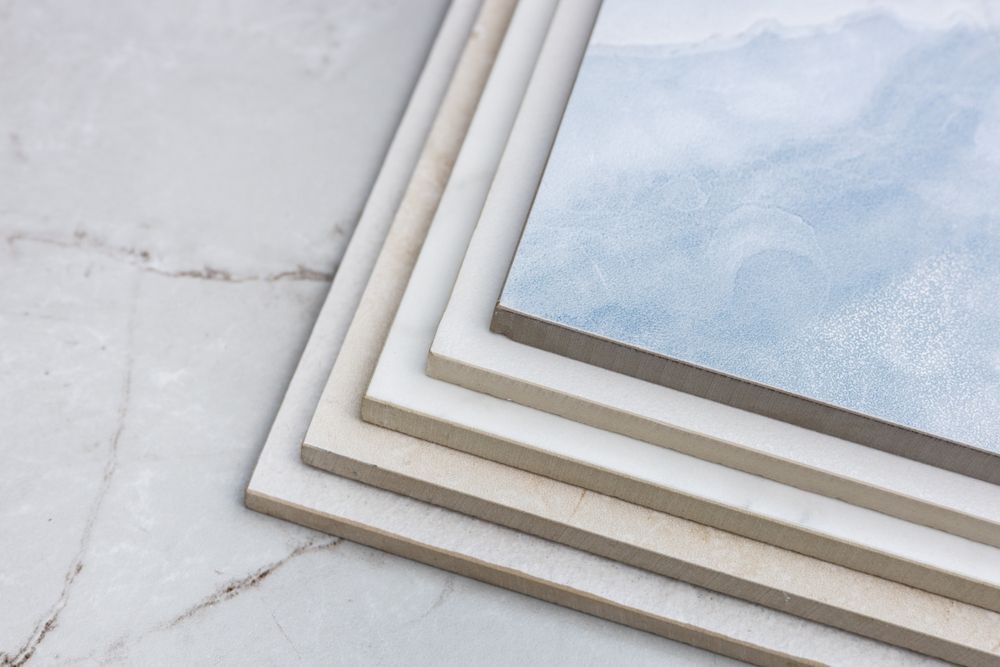 Stacked white photo frames on a marble surface, with one frame showing a pale blue image.