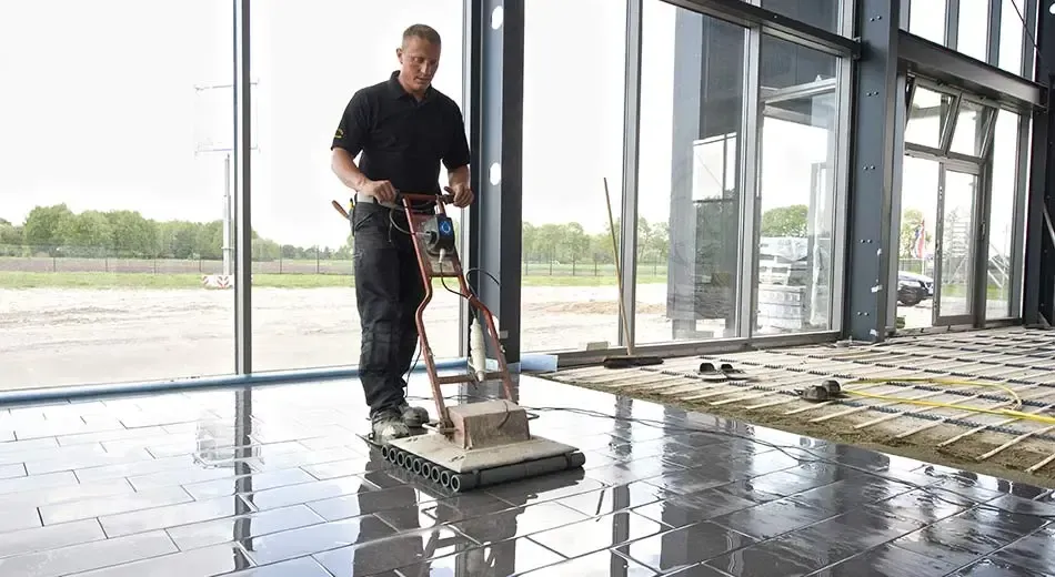 A man is cleaning the floor of a building with a machine.