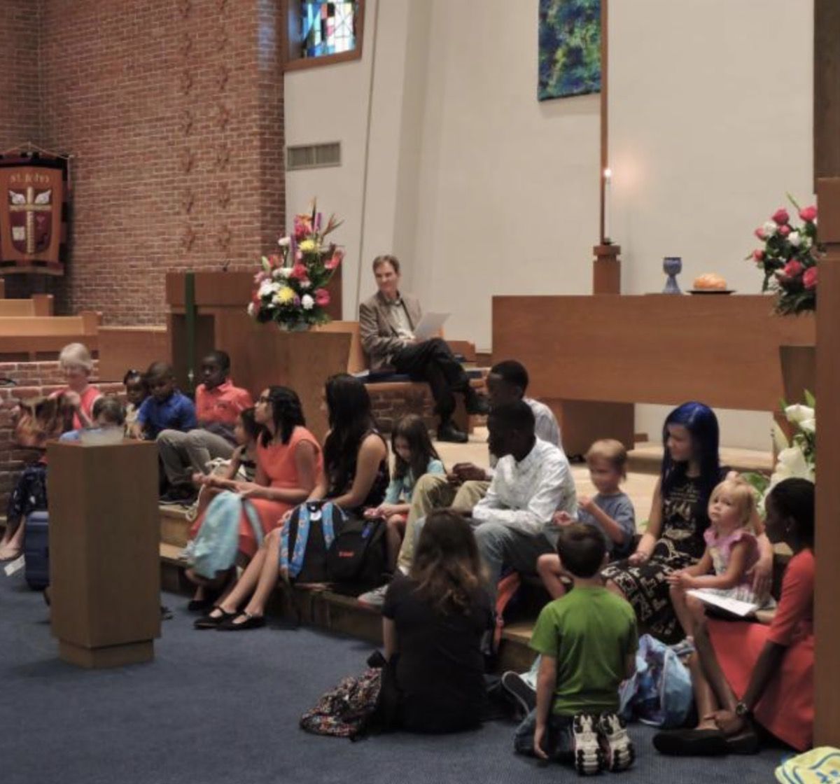 A group of people sit on the floor in a church