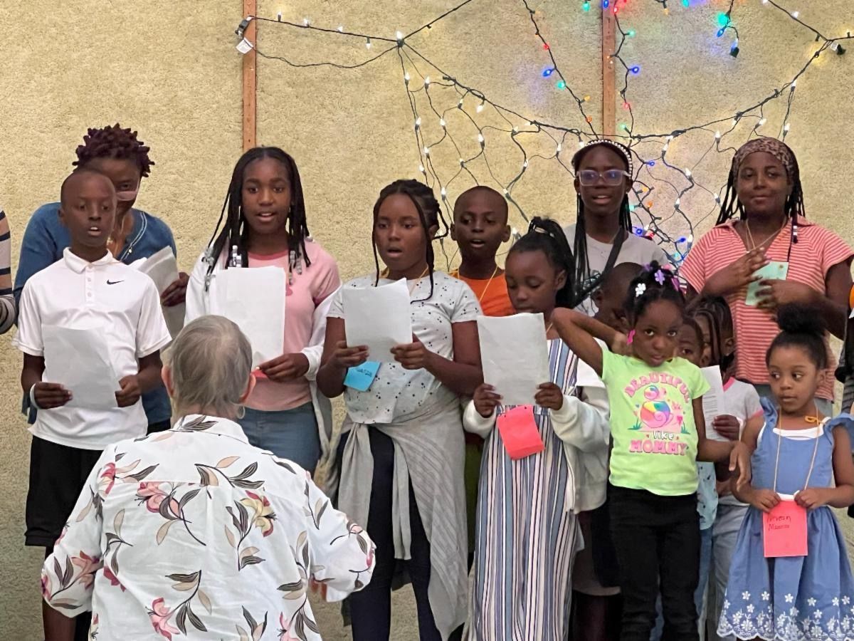 A group of children are singing in front of an elderly woman.