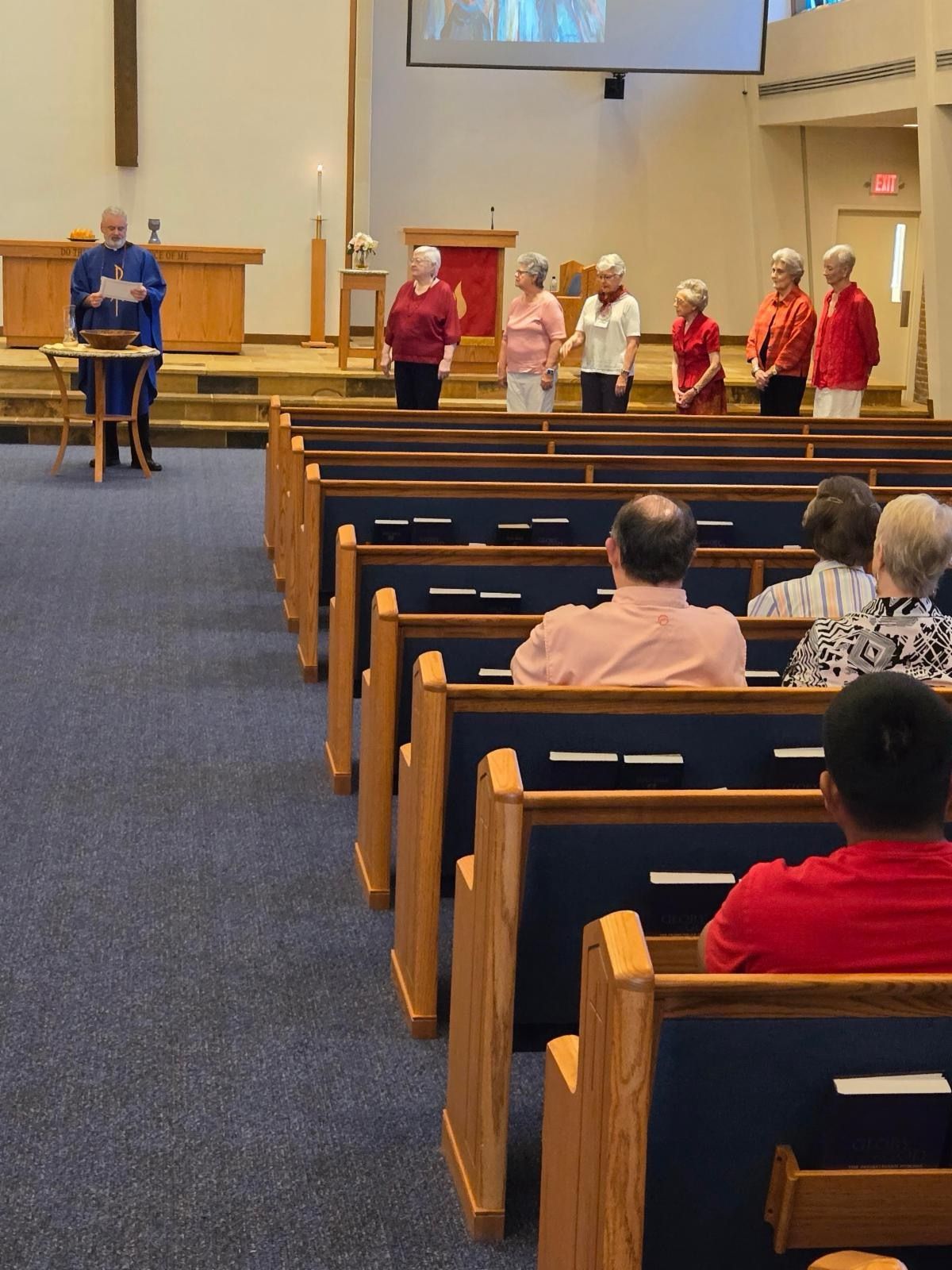 A group of people are sitting in a church watching a presentation