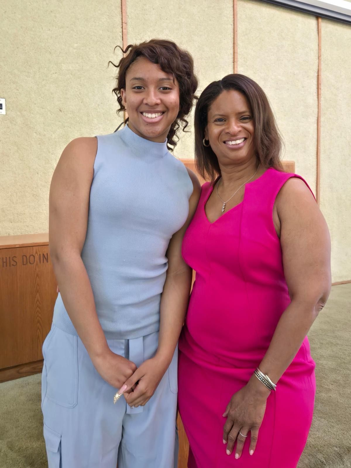 Two women are posing for a picture and one is wearing a pink dress