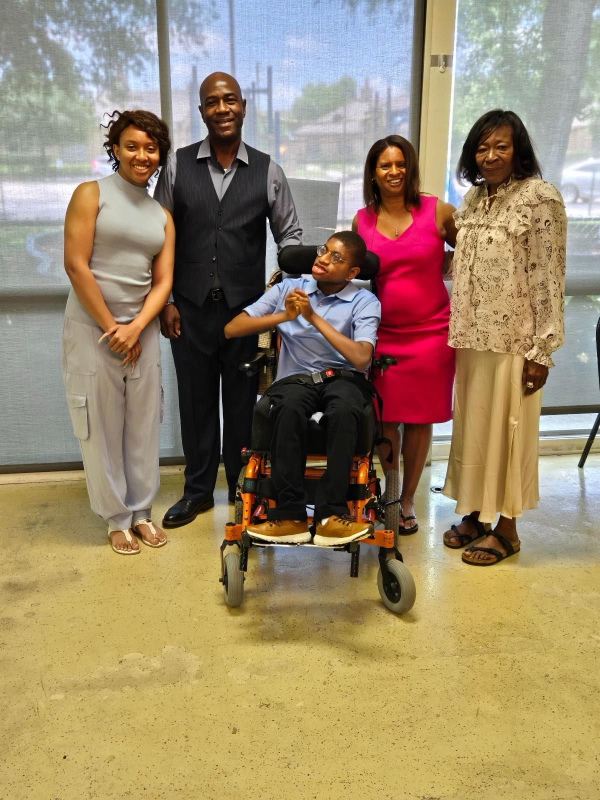 A group of people standing around a boy in a wheelchair