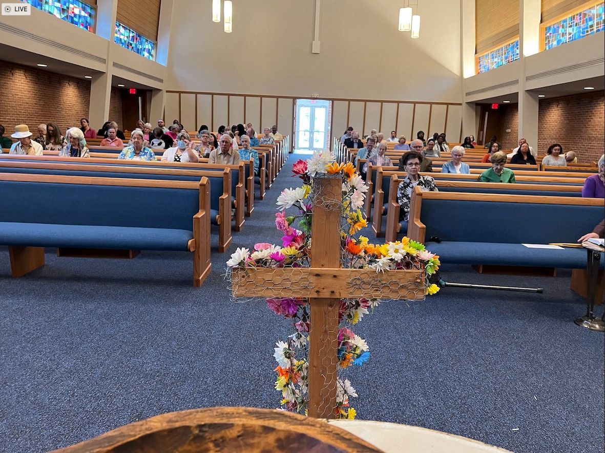A church with a wooden cross decorated with flowers