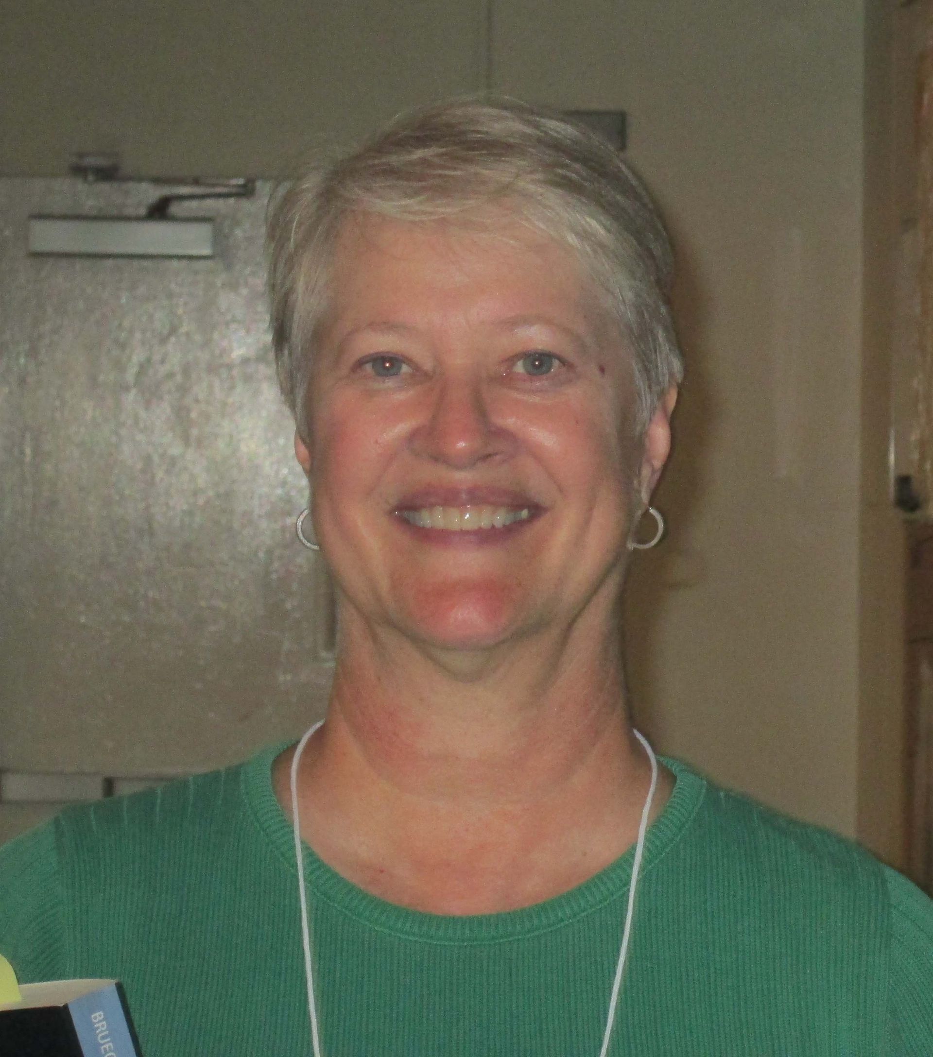 A woman in a green shirt is smiling for the camera