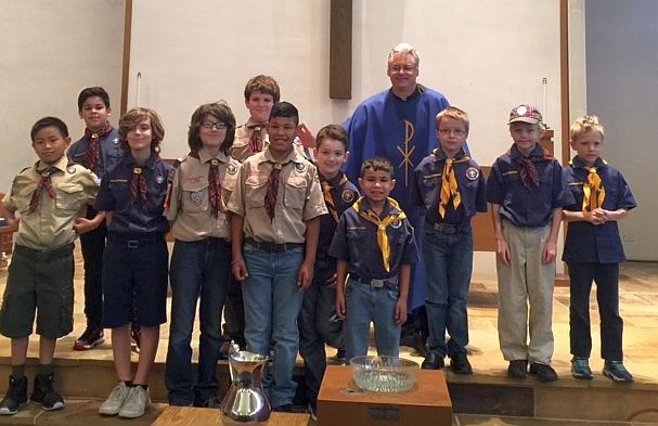 A group of boy scouts are posing for a picture with a trophy.