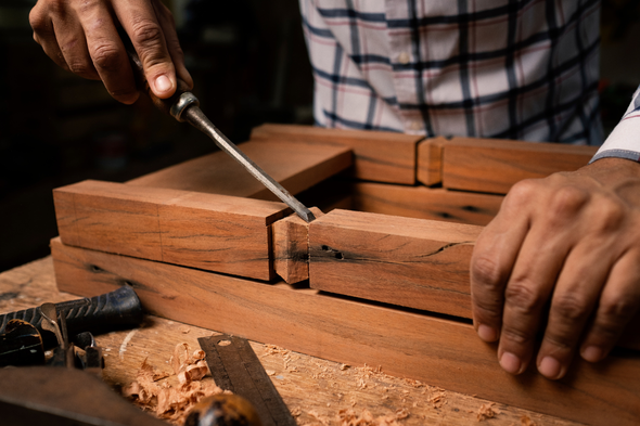 A man is working on a piece of wood with a screwdriver.