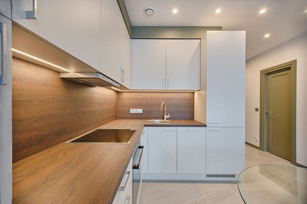 A kitchen with white cabinets , a sink , and a stove top oven.