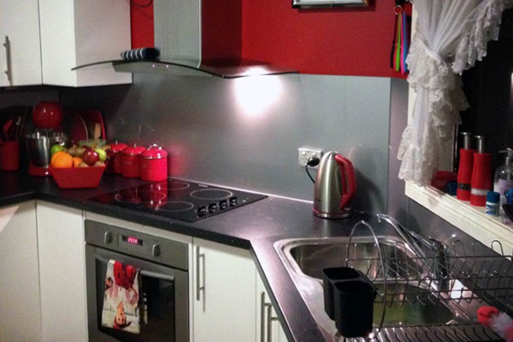 Kitchen with Grey Splashback & Red Cabinets — Windows & Glass Services in Dubbo, NSW