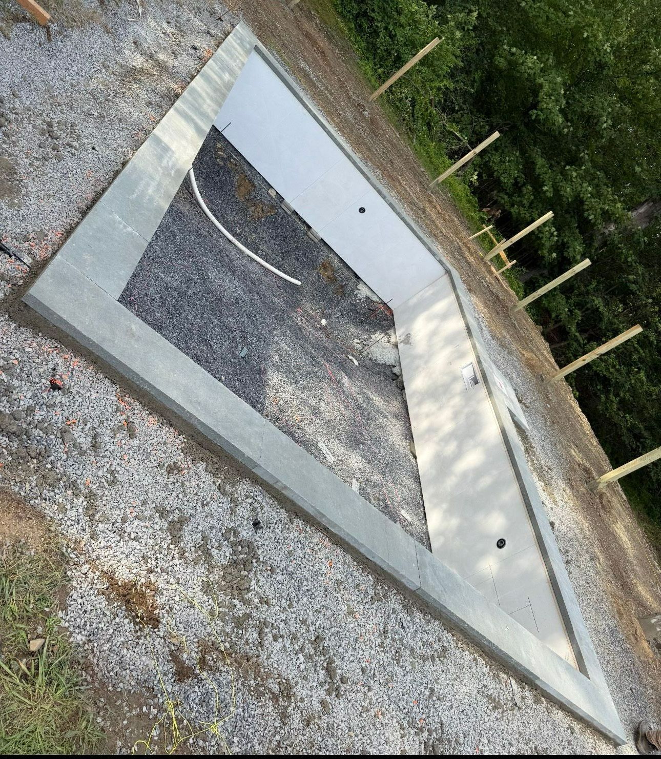 Concrete pool foundation, gravel surround. Includes interior form for a white step or bench.