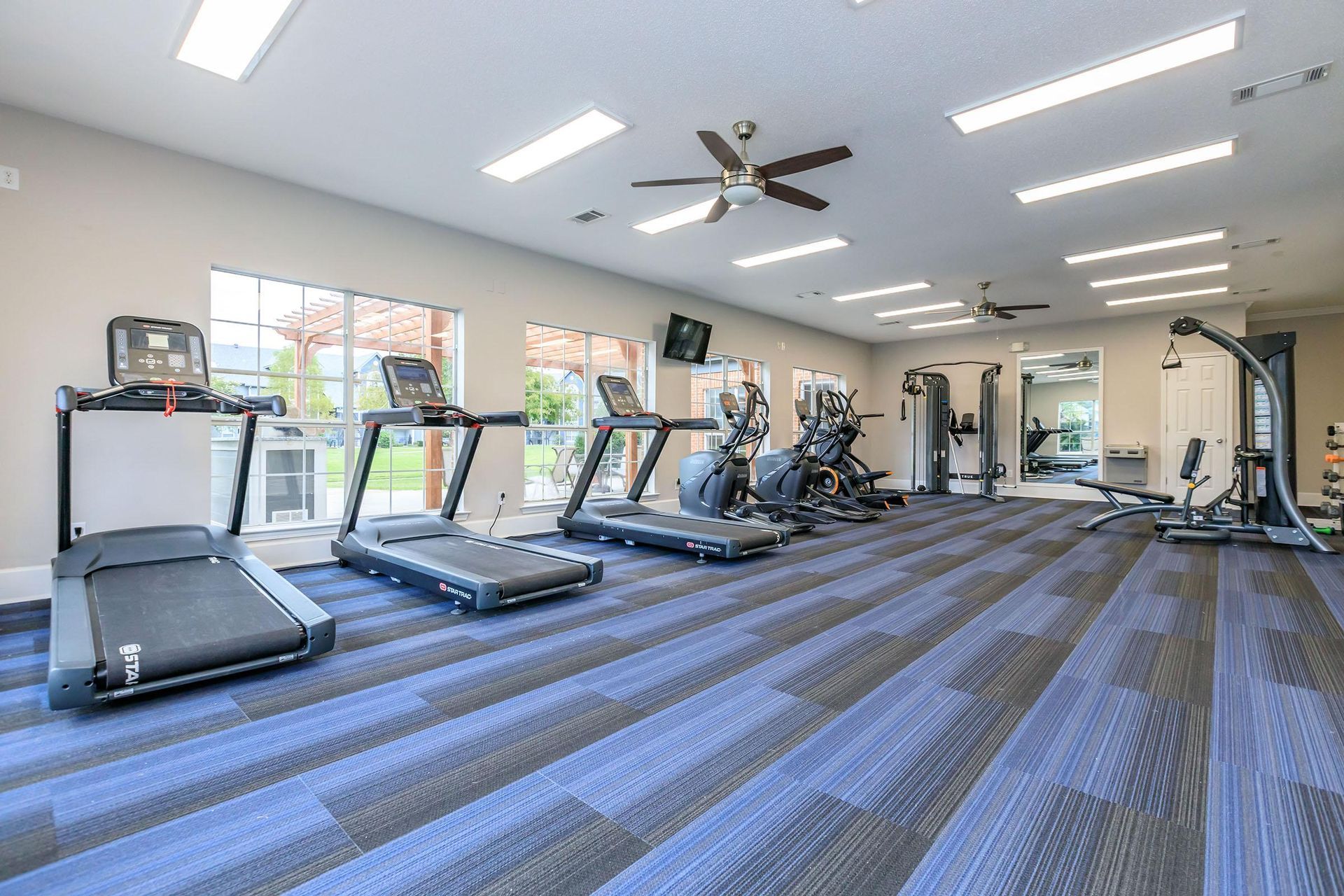 A large gym with treadmills, exercise bikes, and a ceiling fan at Pelican Pointe in Slidell, LA.