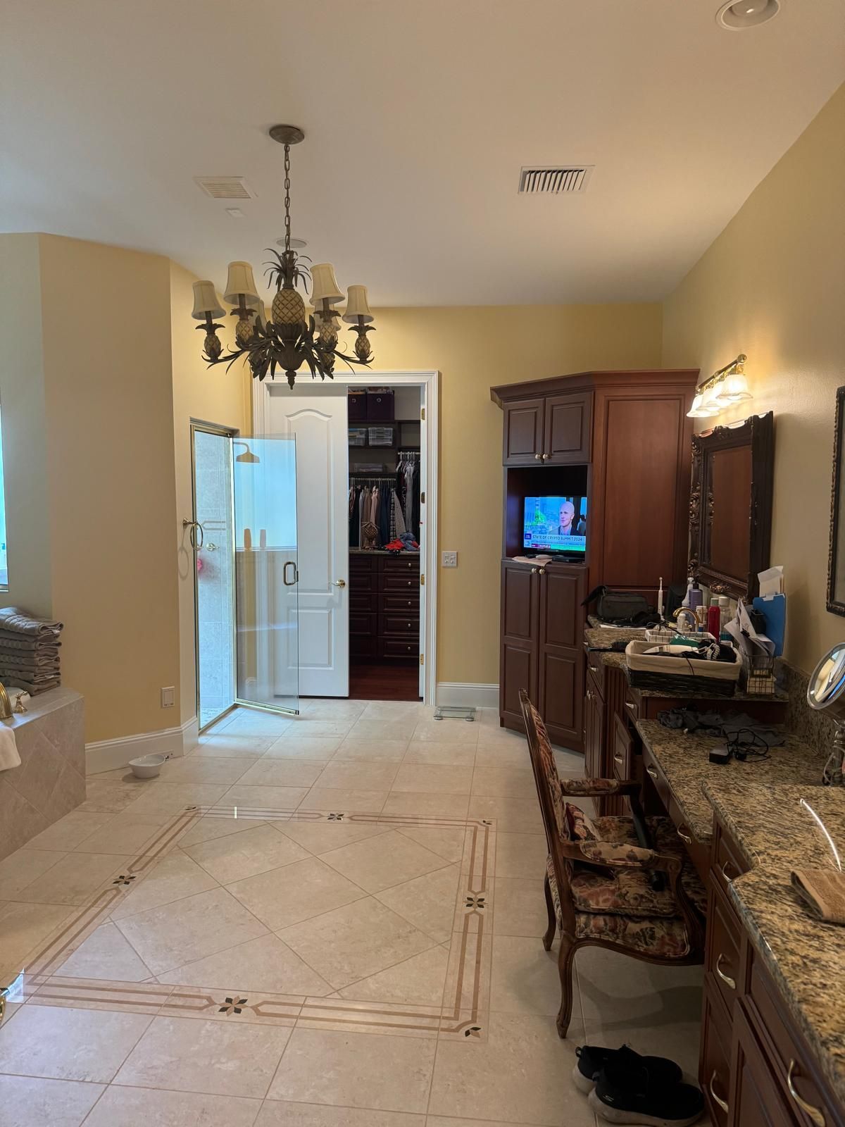 A bathroom with a chandelier hanging from the ceiling and a walk in closet.