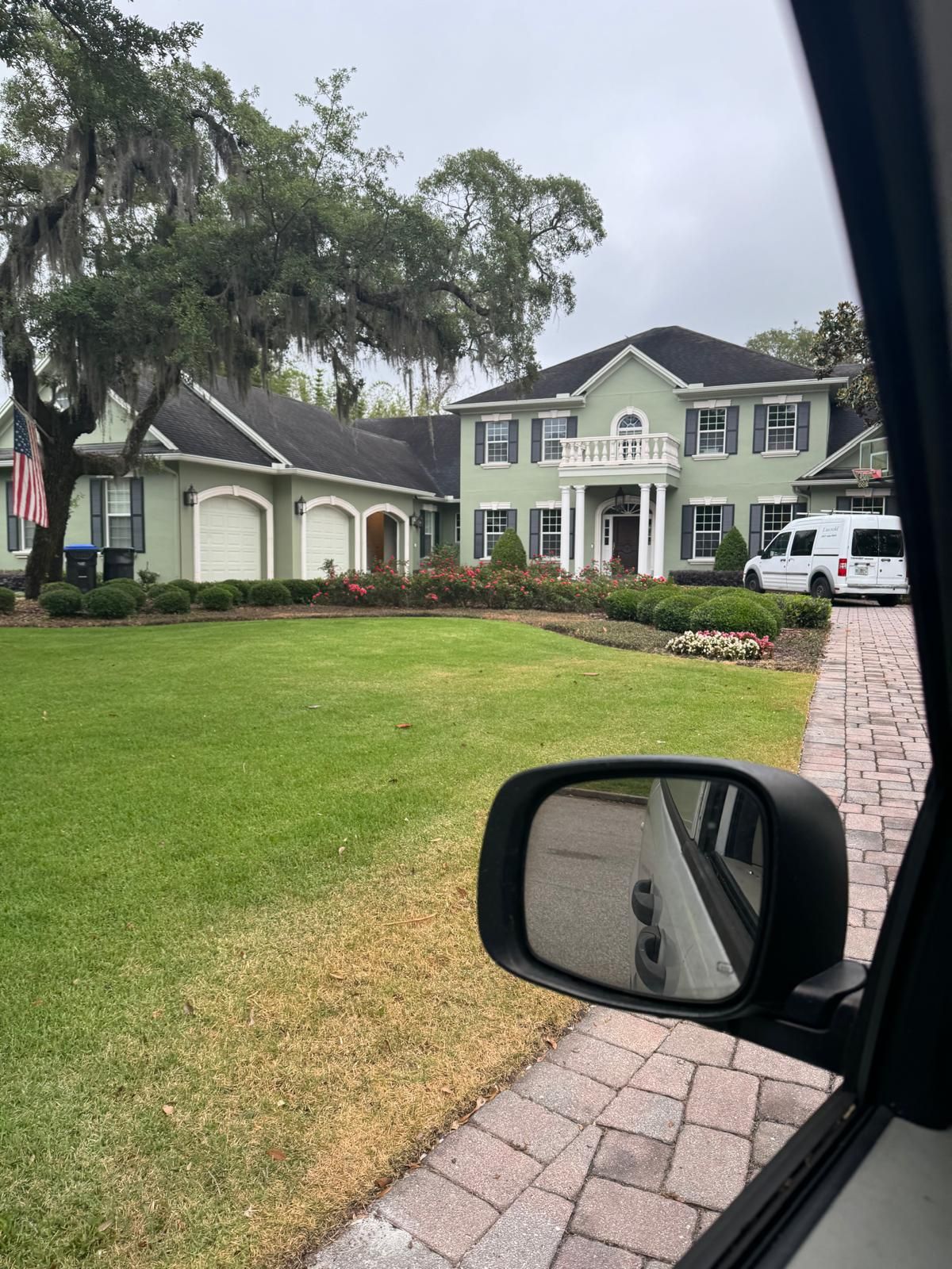 A car is parked in front of a large house.