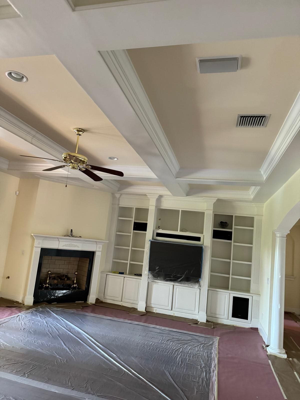 A living room with a fireplace and a ceiling fan.