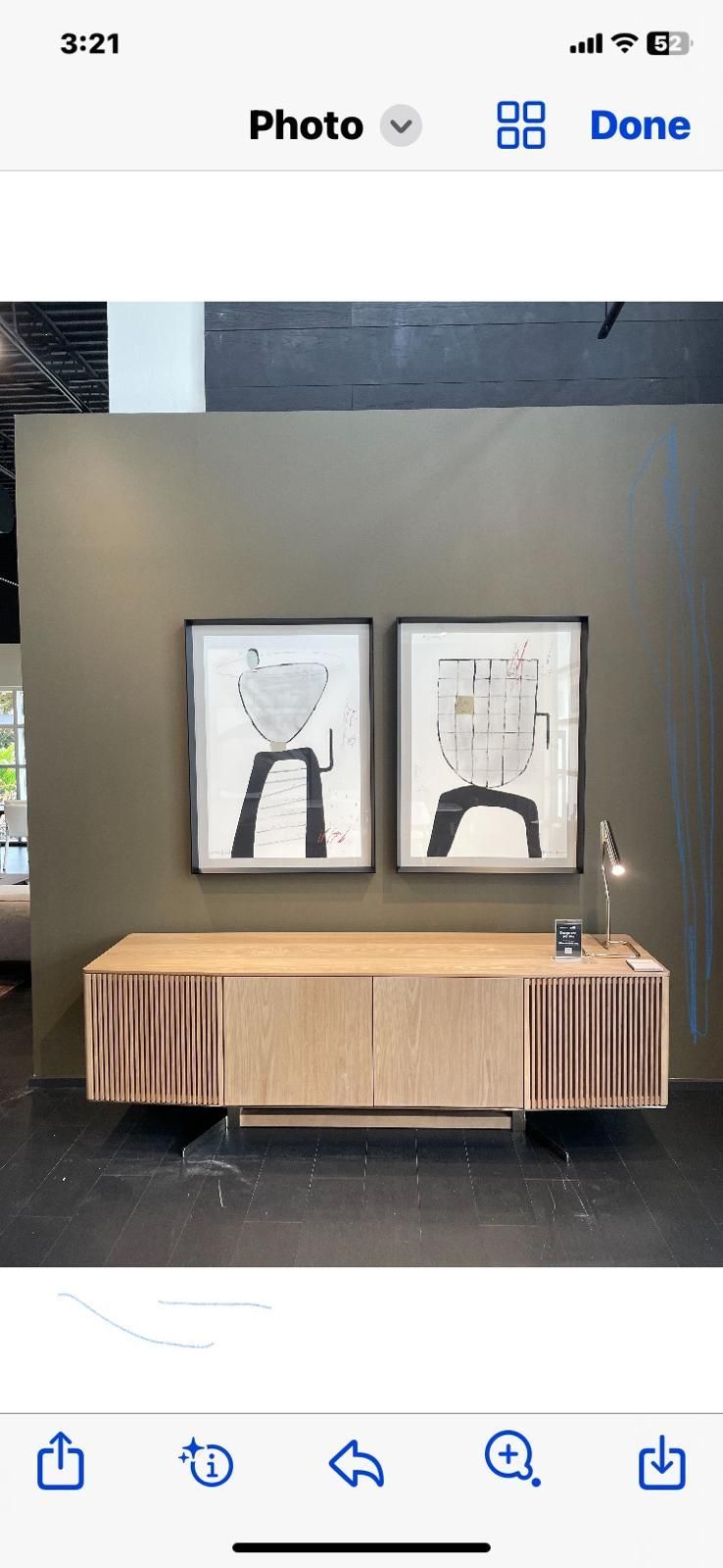 Two paintings are hanging on a wall above a wooden cabinet.