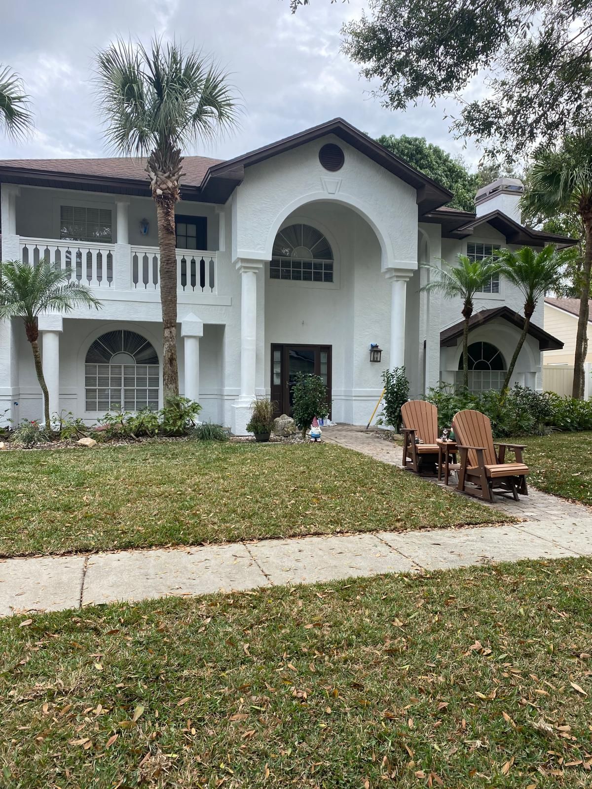 A large white house with two wooden chairs in front of it.