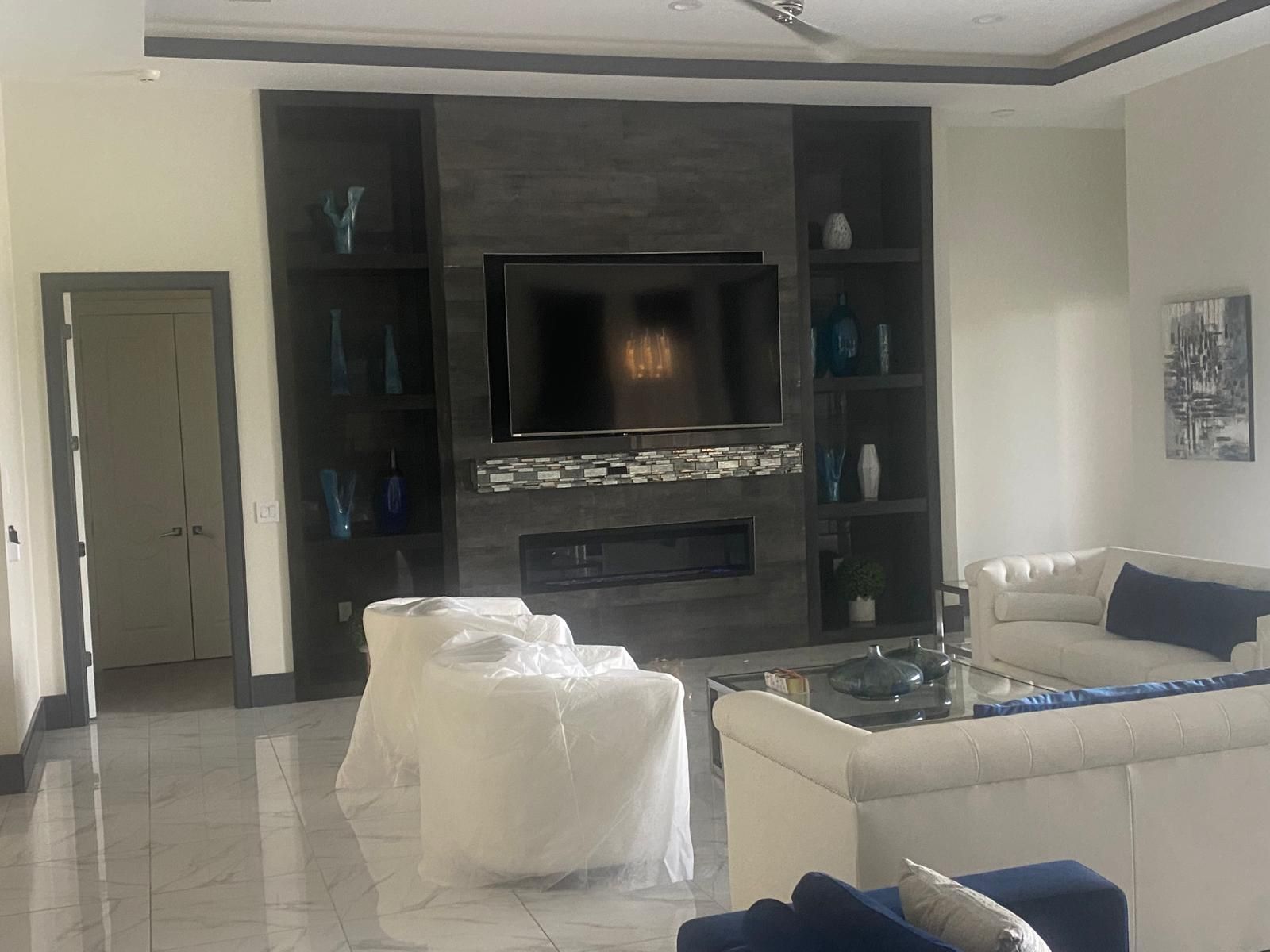 A living room with a couch , chairs , television and fireplace.