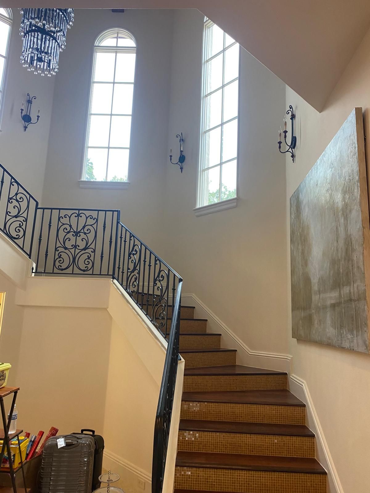 A staircase in a house with a wrought iron railing and lots of windows.