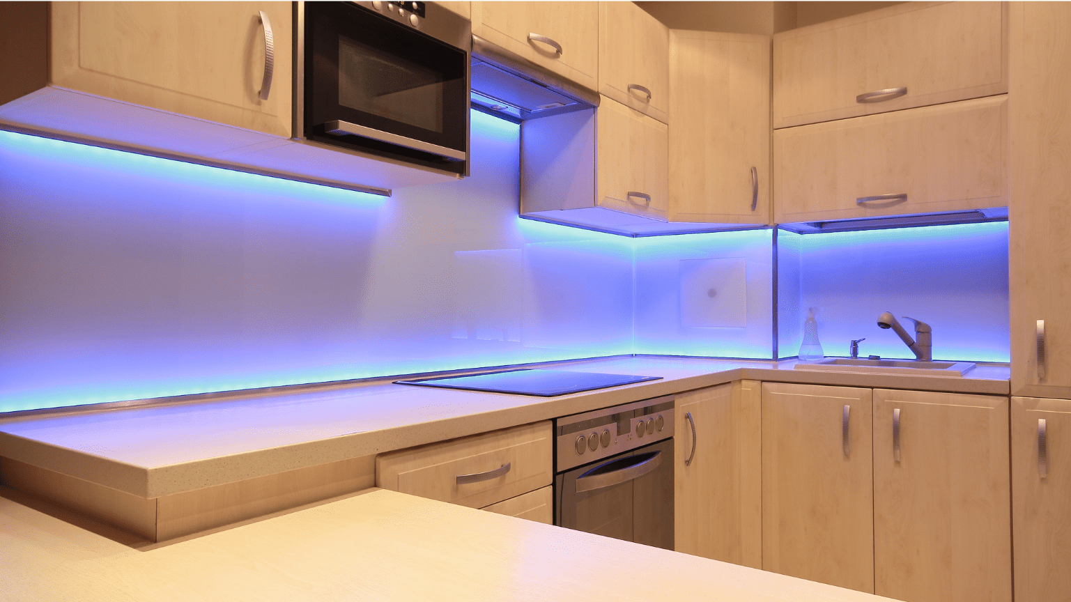 Modern kitchen with light wood cabinets, blue LED strip lighting, and stainless steel appliances — Intolec Electrical In Tweed Heads, NSW