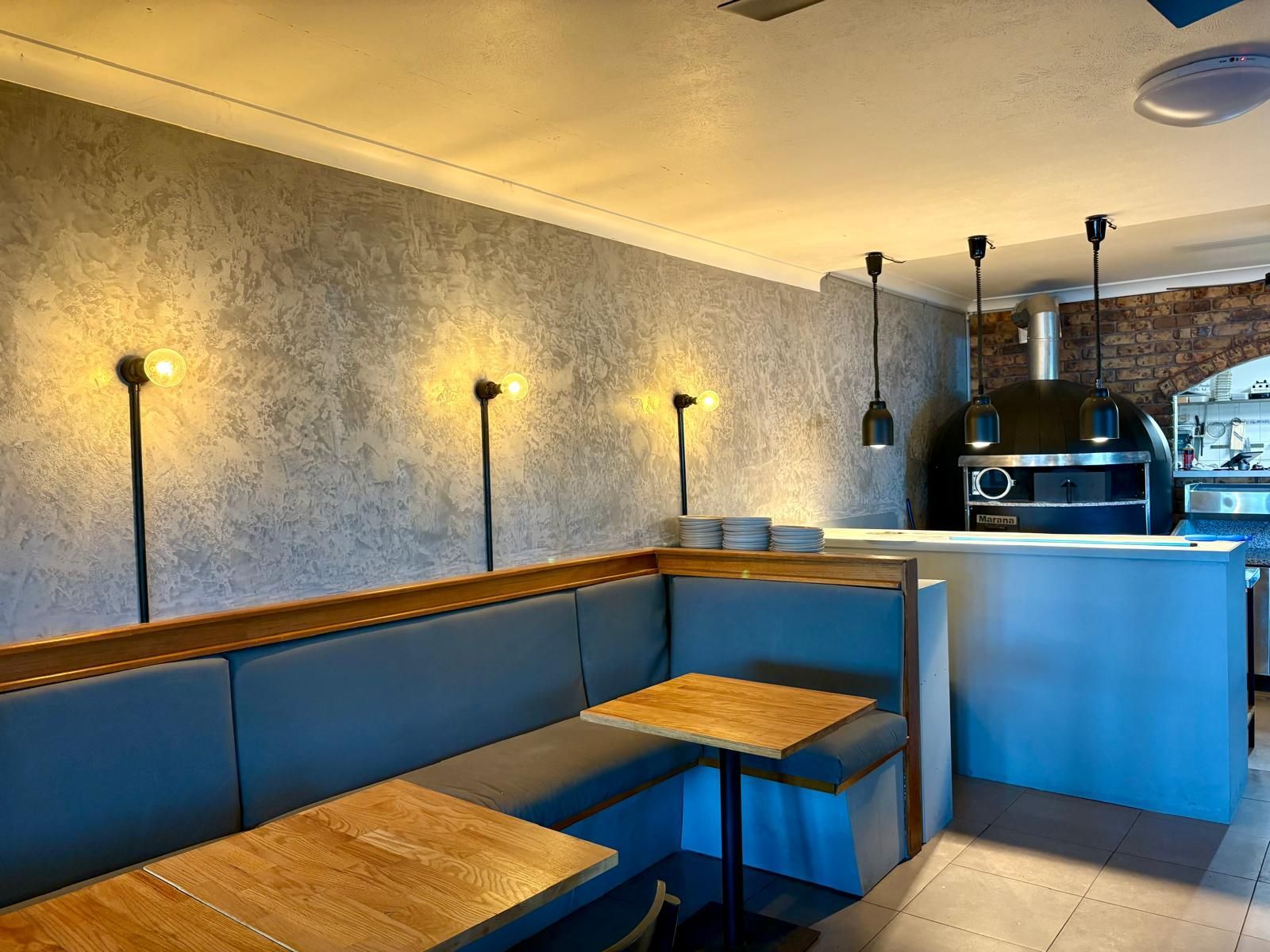 Cozy Restaurant Interior With Booth Seating, Wooden Tables, and a Pizza Oven — Intolec Electrical in Tweed Heads, NSW