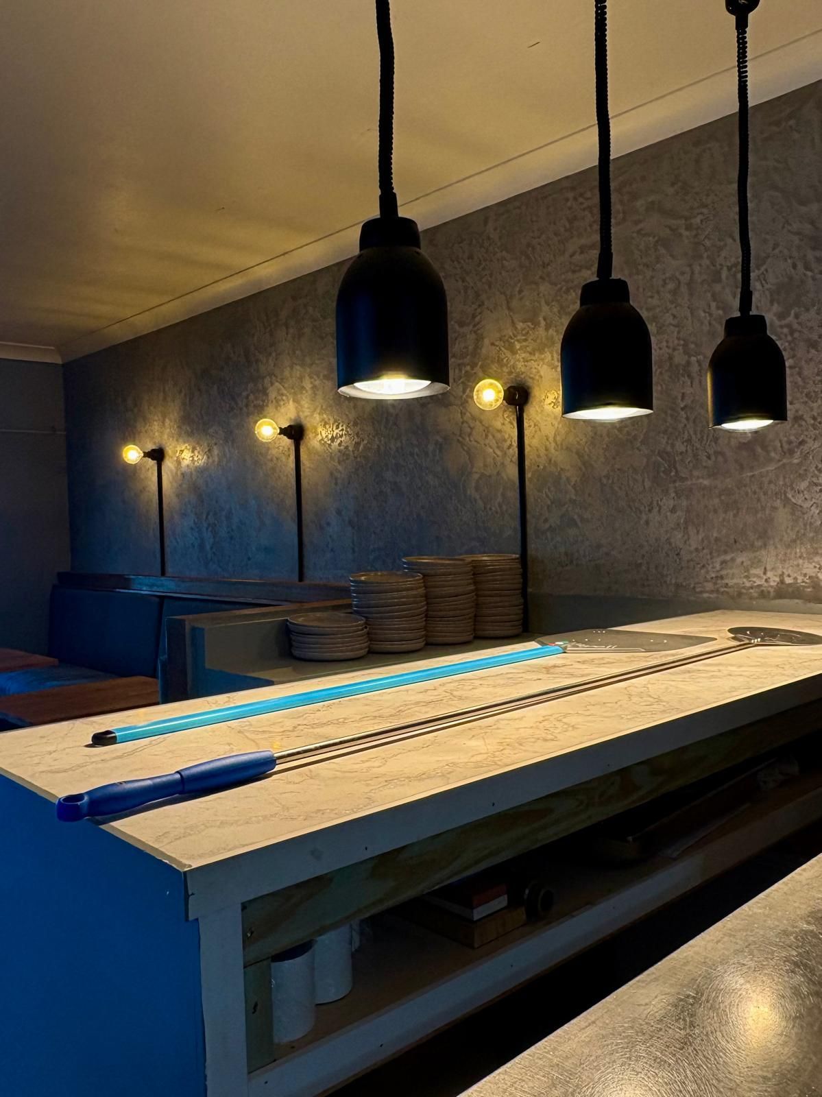 Three Black Pendant Lights Illuminate a Long Wooden Bar — Intolec Electrical in Tweed Heads, NSW