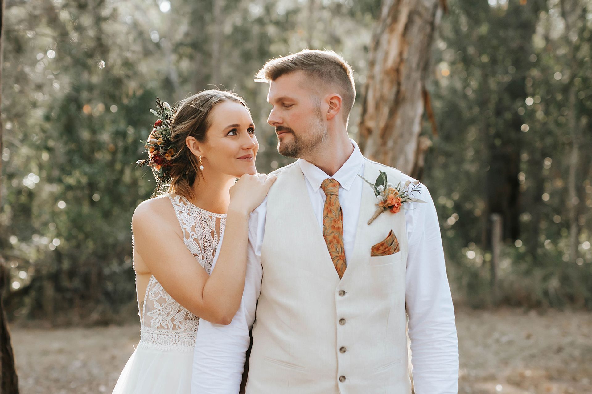 Bride and groom looking at each other outside in Northern NSW, sunlight. The bride has a flower headpiece.
