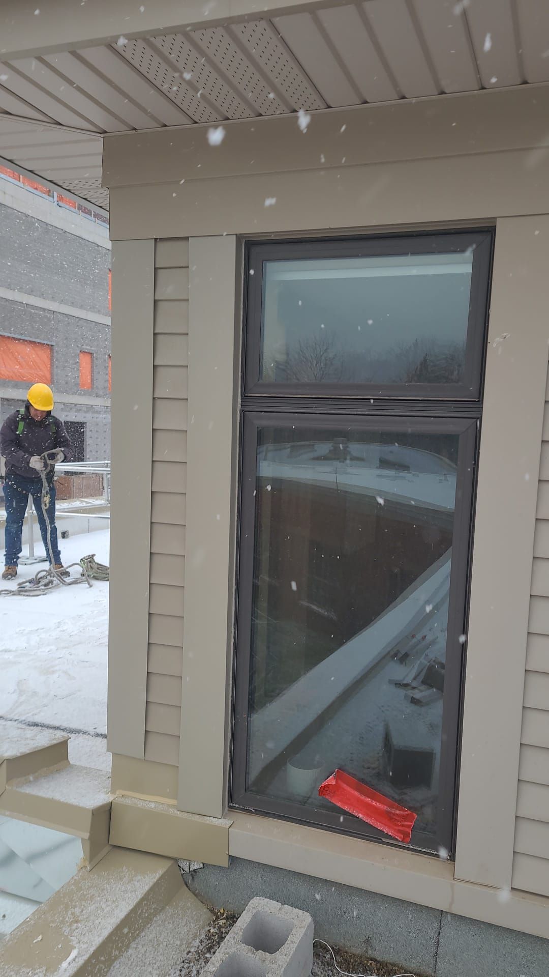 A man is standing next to a window on the side of a building.