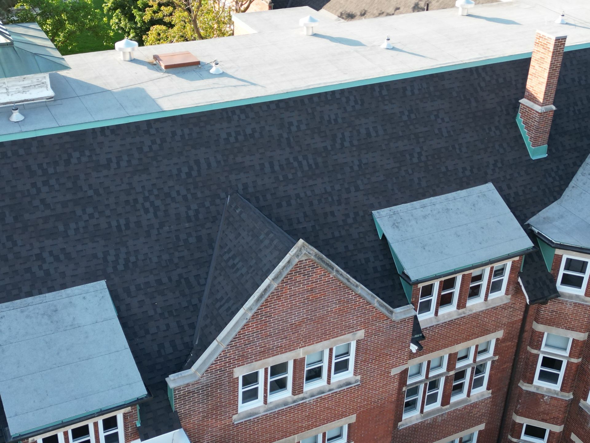 An aerial view of a brick building with a black roof