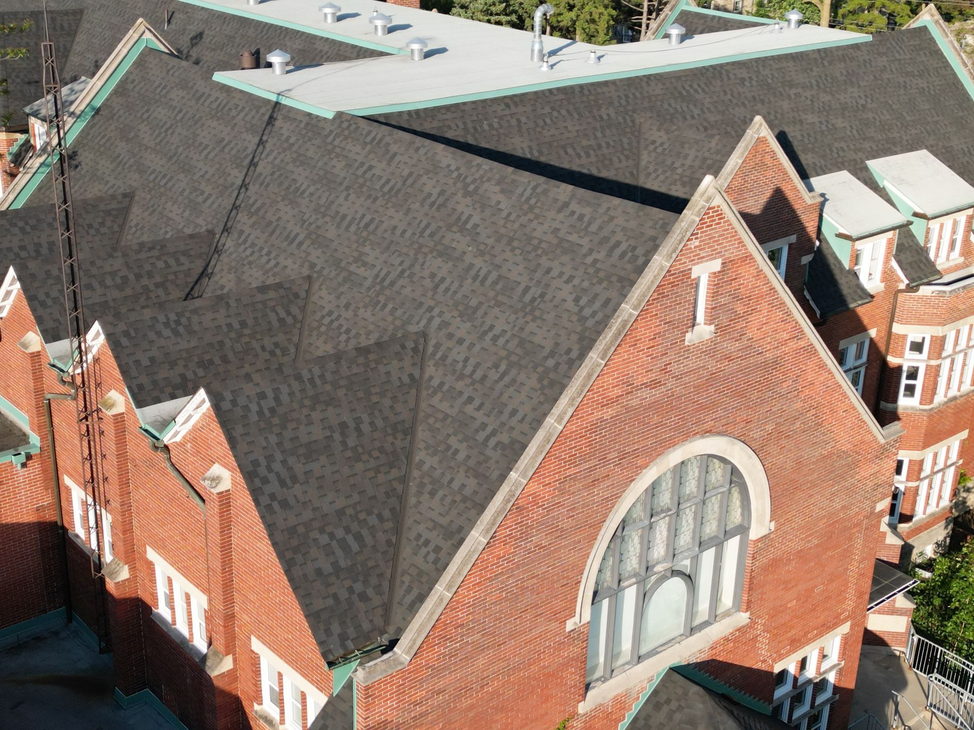 Brick building with dark shingled roofs and arched window.