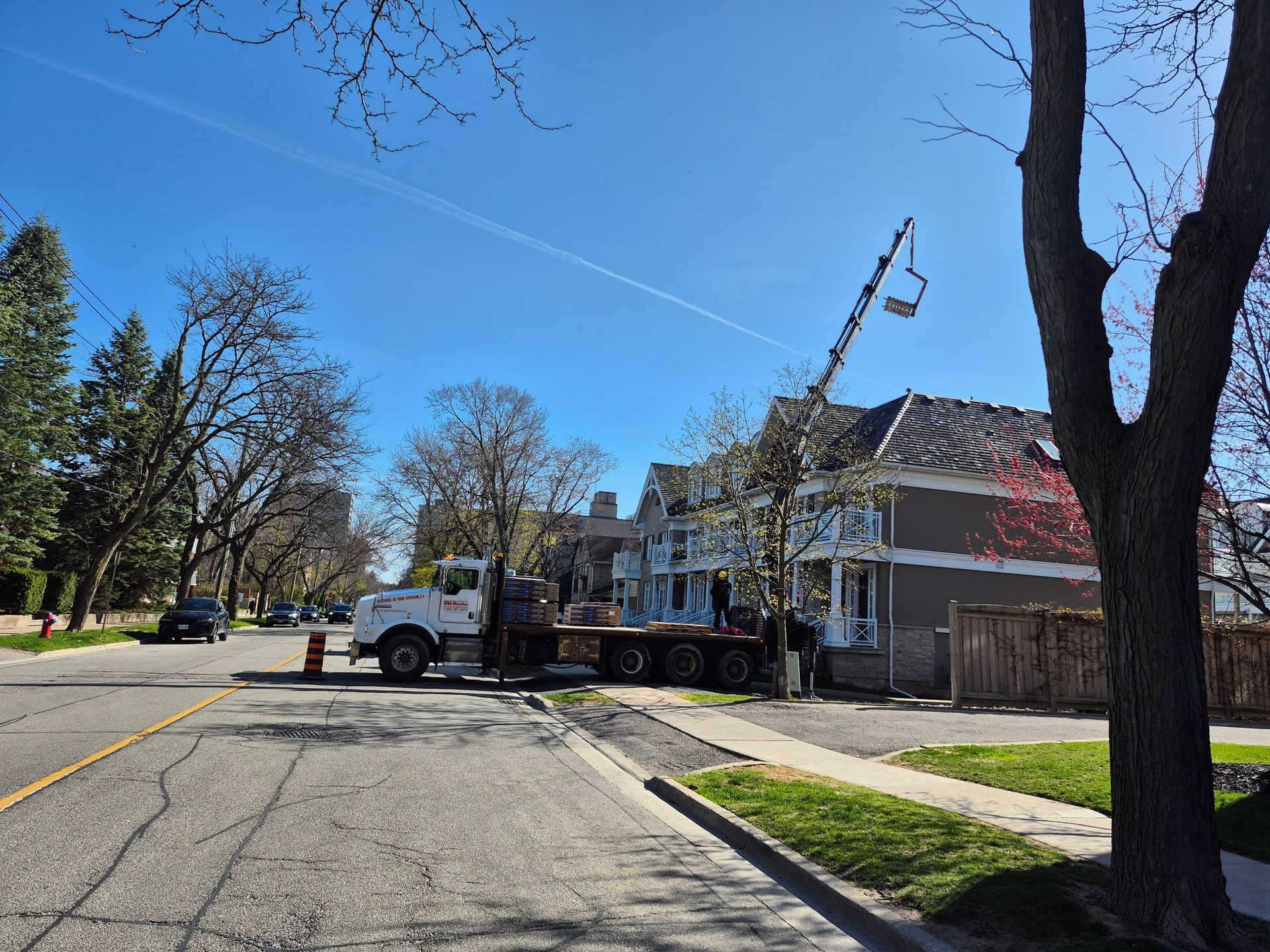 A white truck is parked on the side of the road in front of a house.