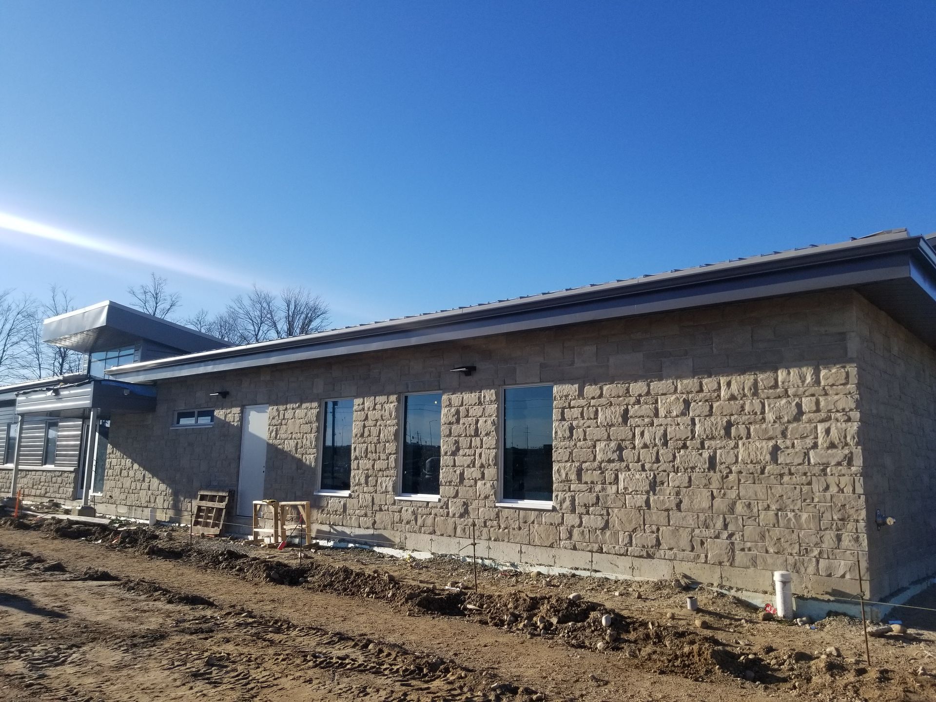 A brick house is being built in a dirt field.