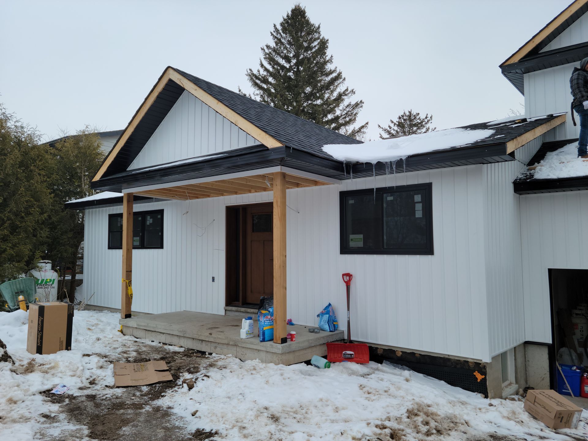 A white house with a black roof is being built in the snow.
