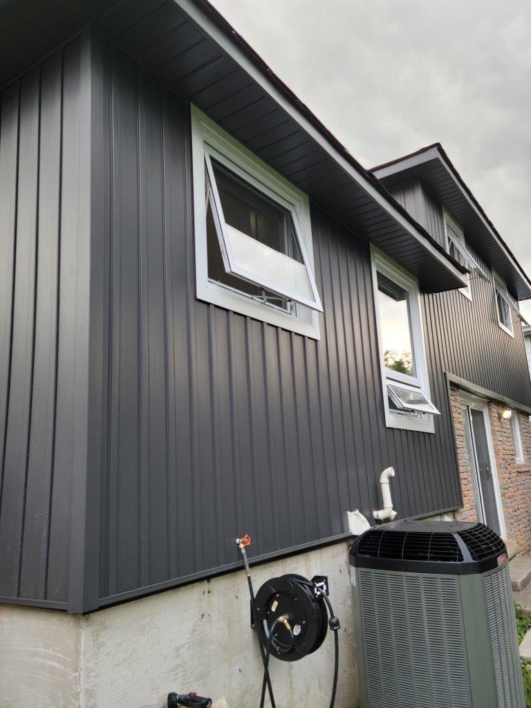 A house with a black siding and a window on the side.