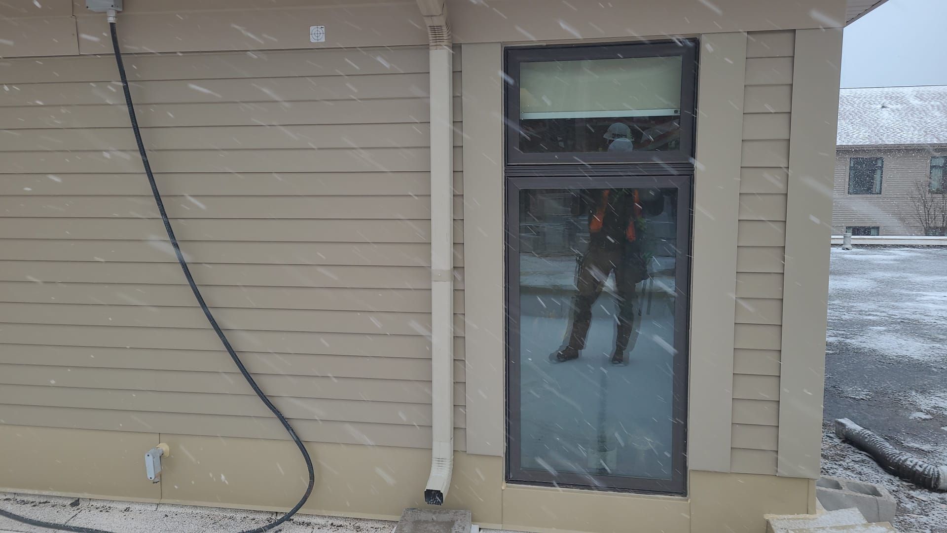 A person is standing in front of a window on a snowy day.
