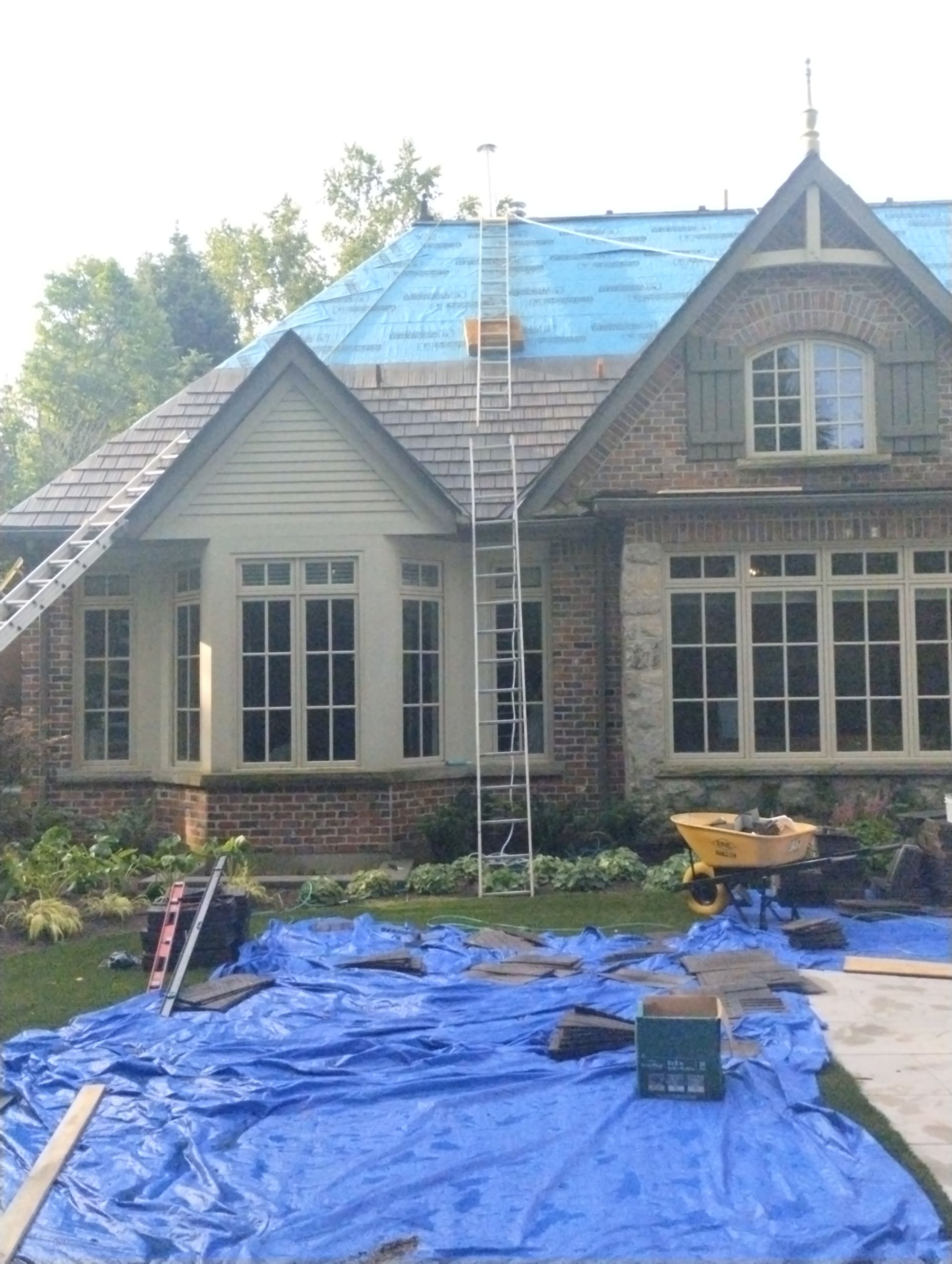 A house with a blue tarp on the ground in front of it