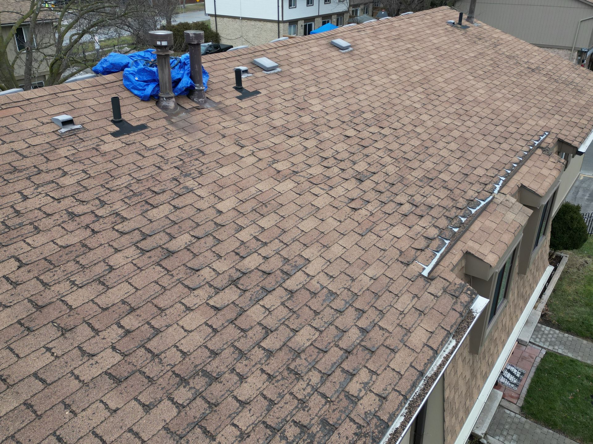 An aerial view of a roof with a blue tarp on top of it.