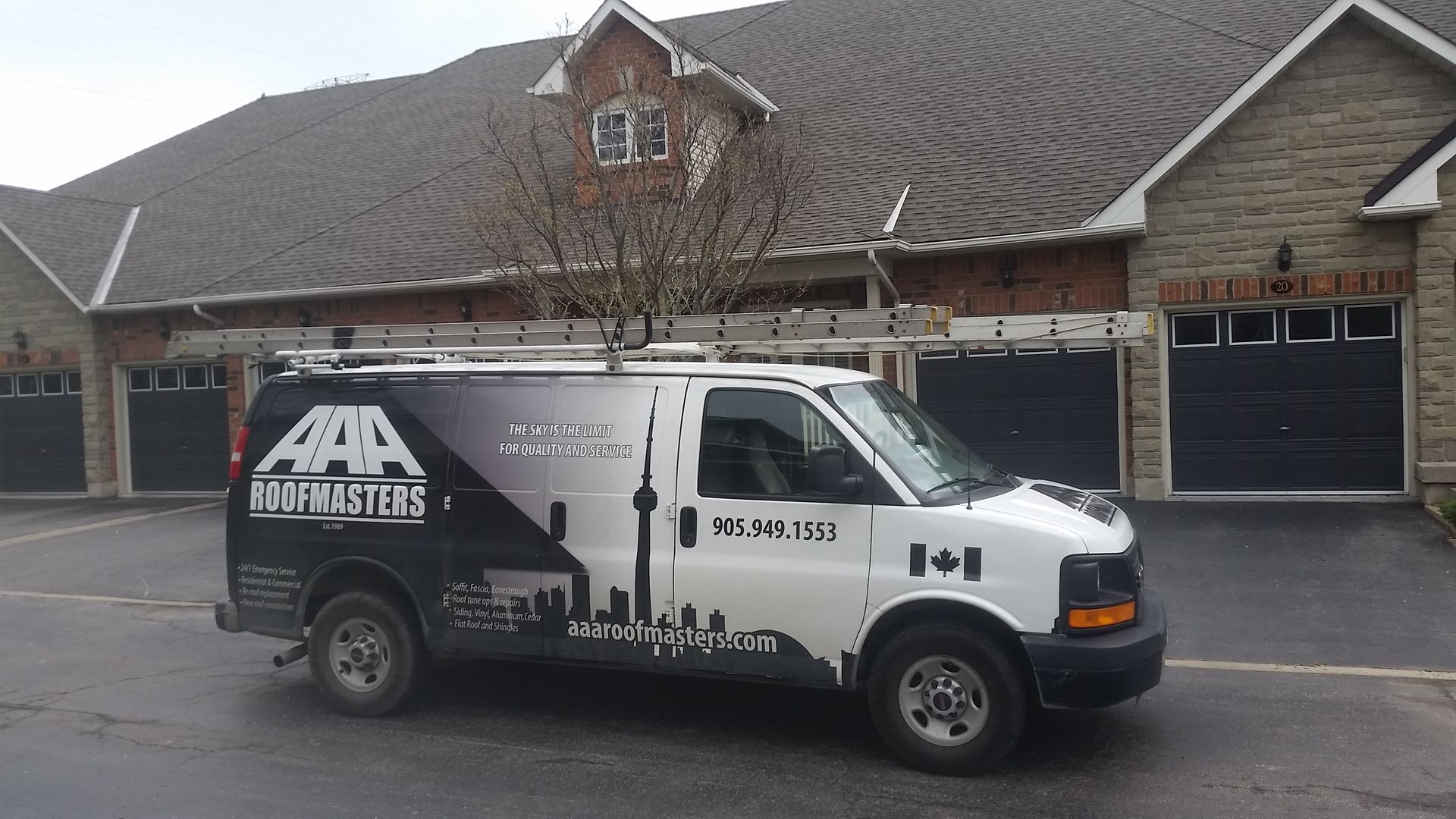 White van with ladder on top parked in front of brick houses. The van has company logo on the side.