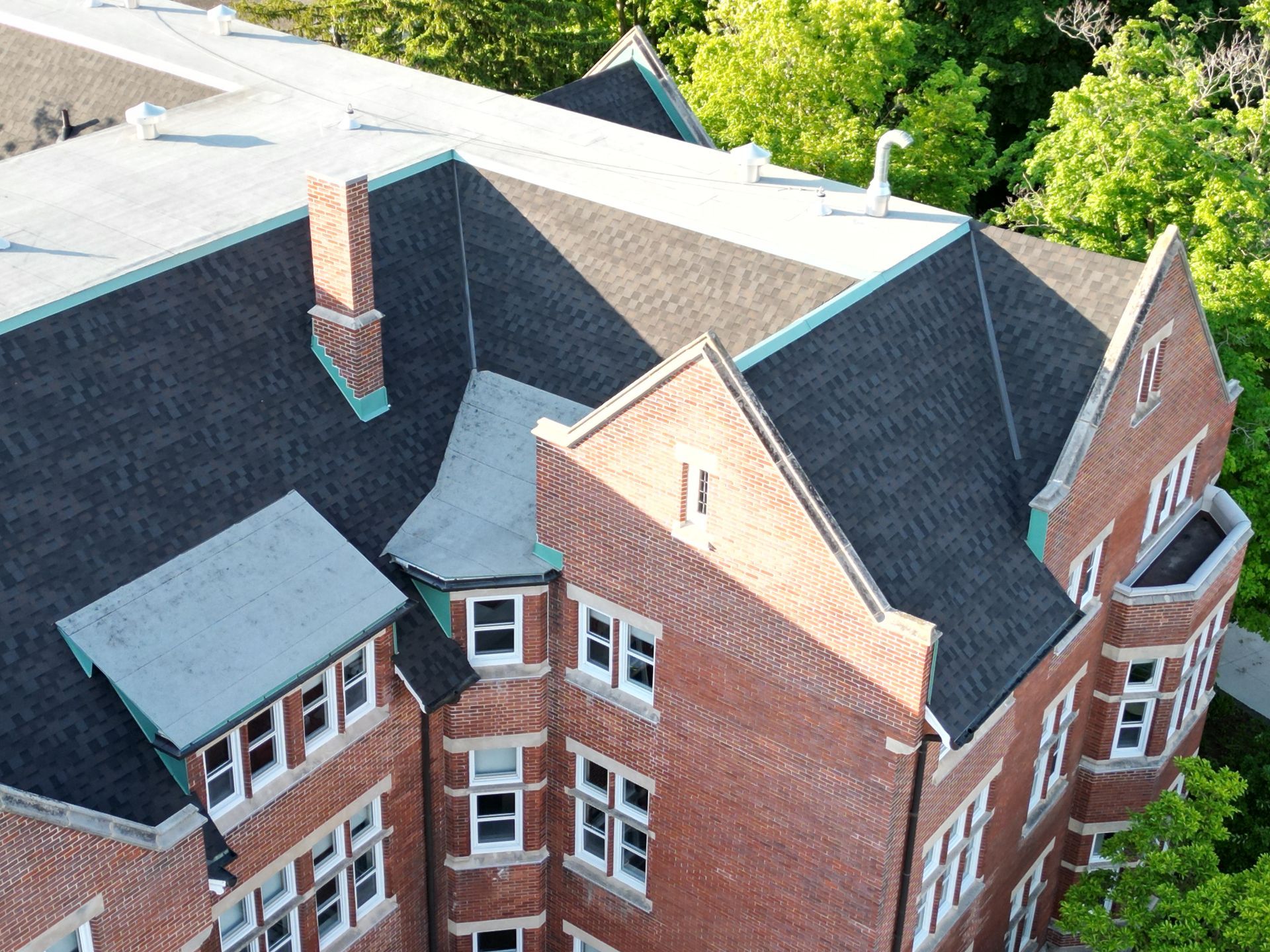 An aerial view of a large brick building with a black roof