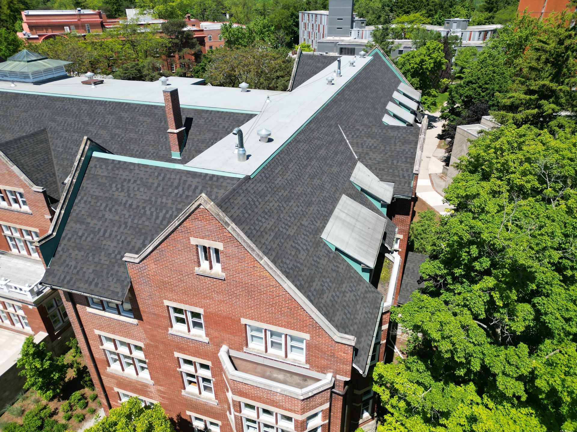 An aerial view of a large brick building with a black roof
