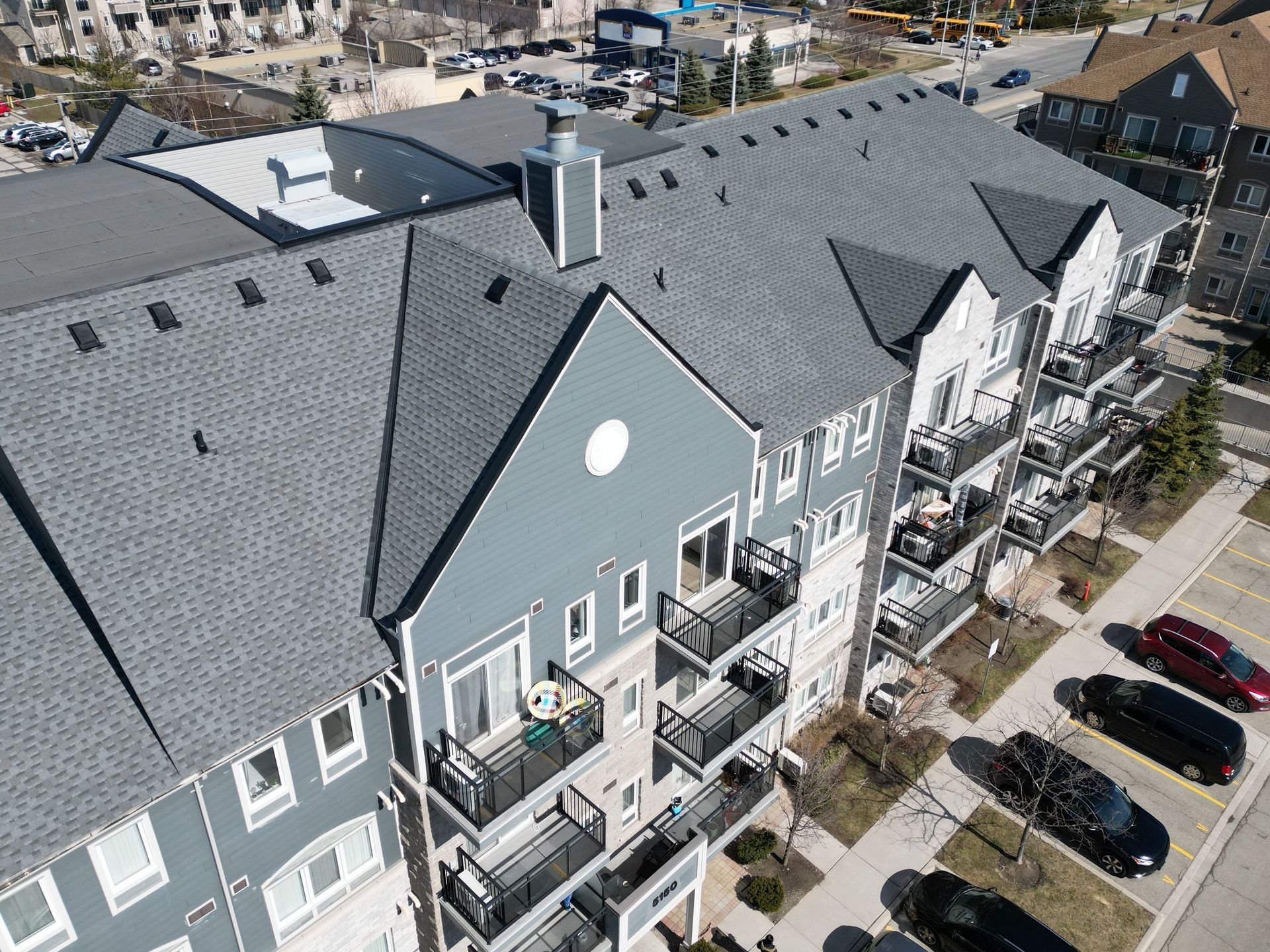 An aerial view of a large apartment building with cars parked in front of it.