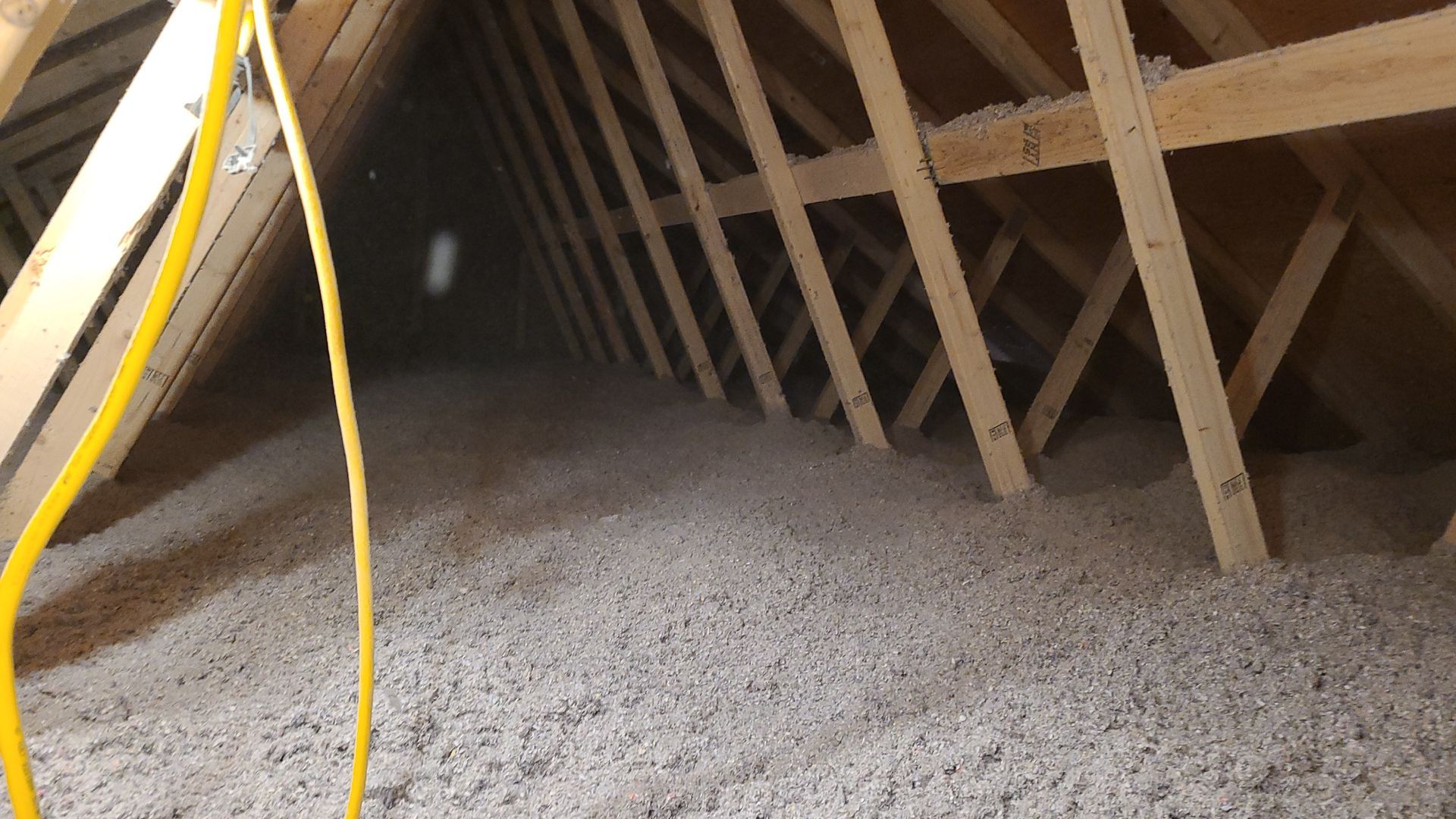 An attic with a lot of insulation and wooden beams