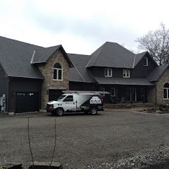 A white van is parked in front of a large house.