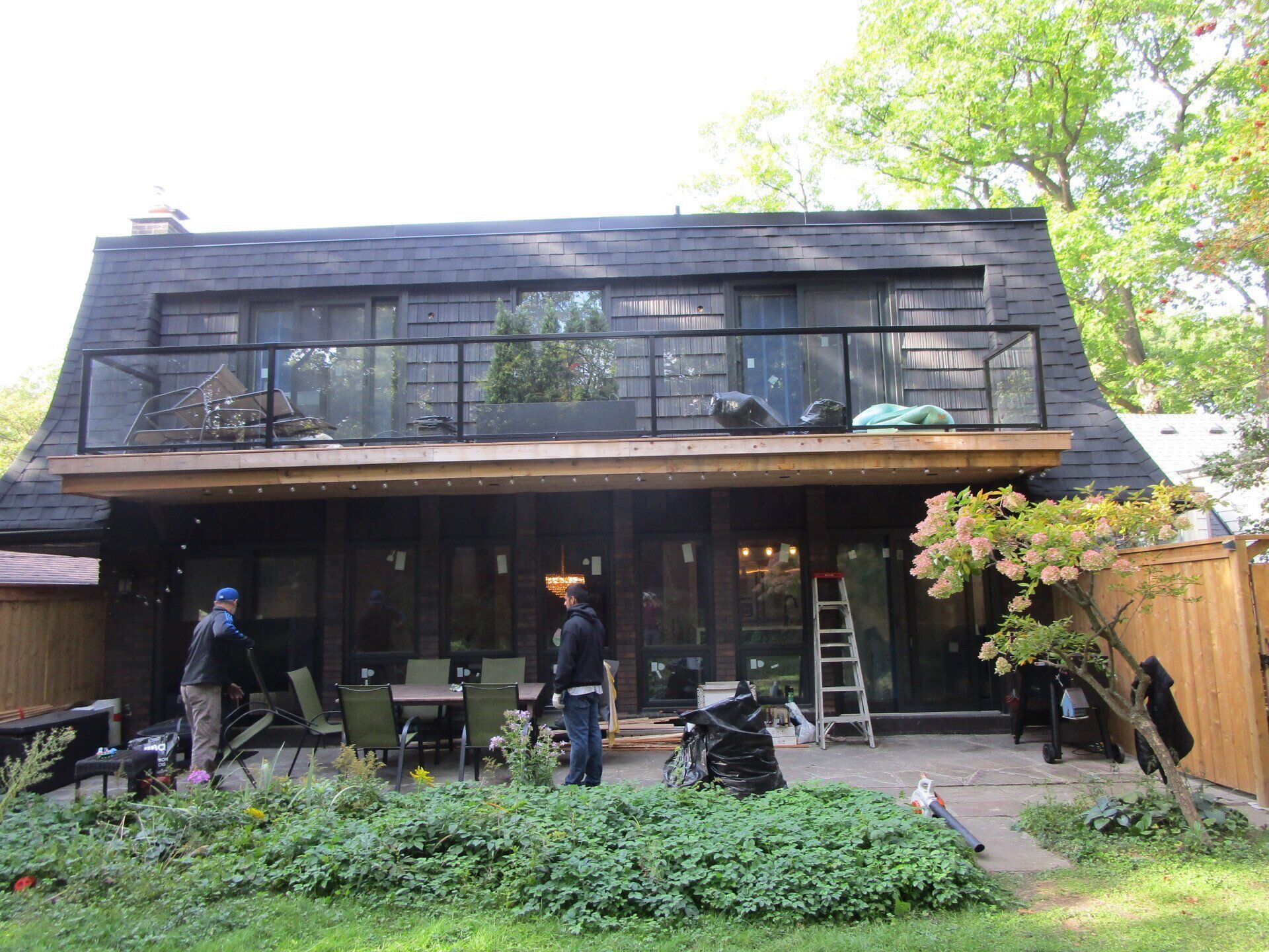A man is standing in front of a house with a balcony.