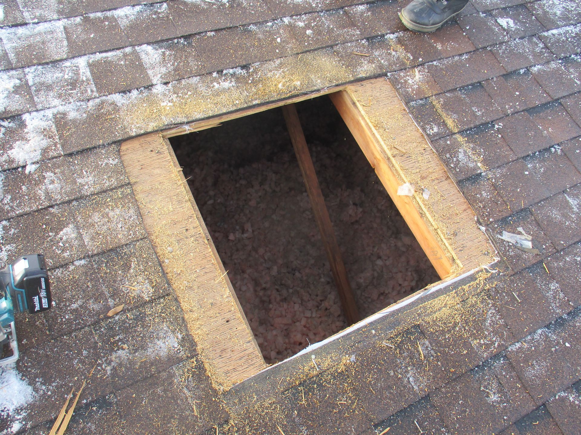 A hole in the roof of a house with insulation in it