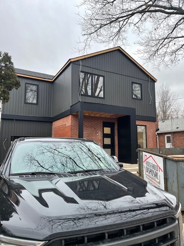 A black truck is parked in front of a house under construction.